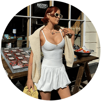 woman in a white top and matching skirt standing on stairs